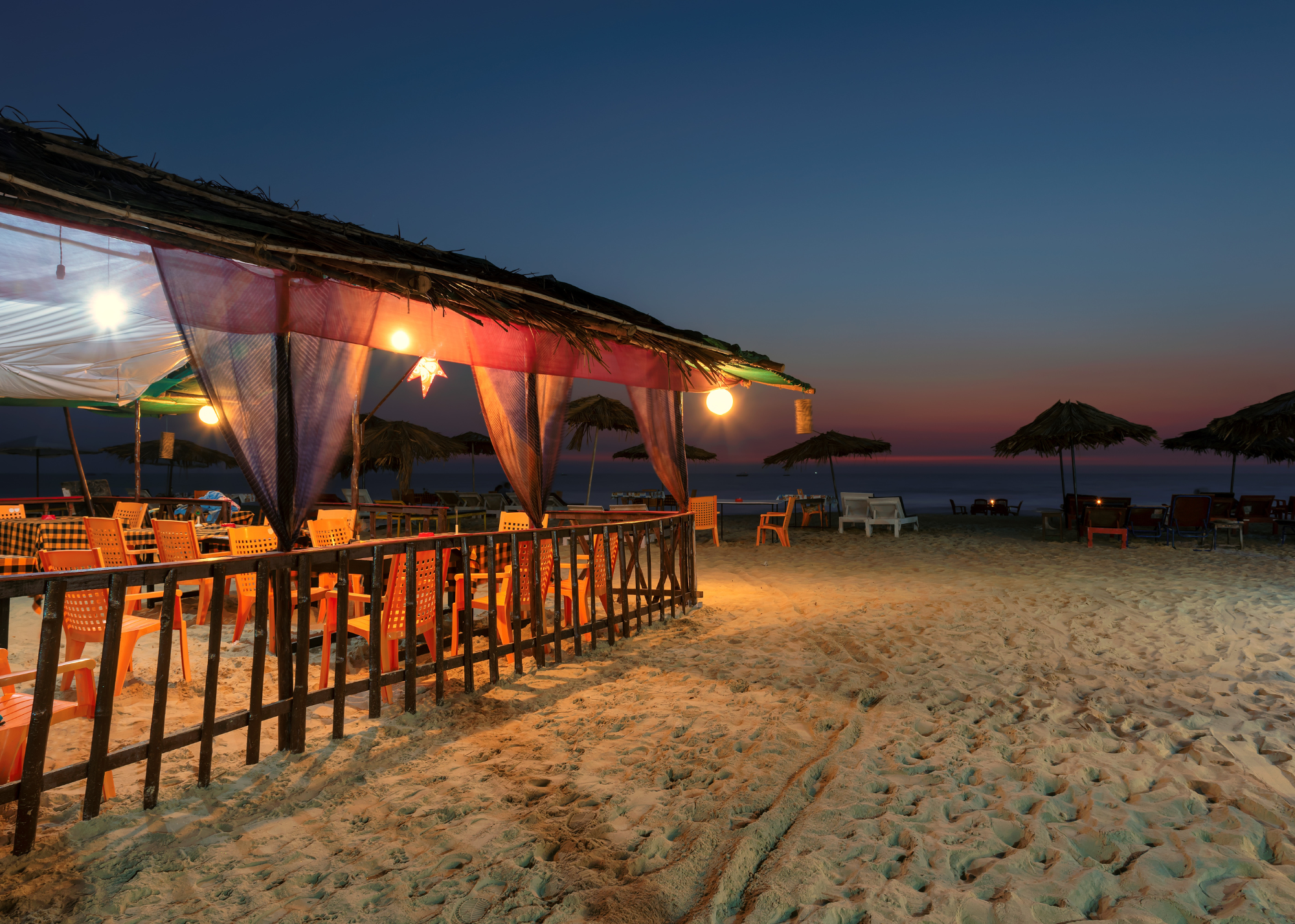 Lantern-lit beach bar on the sand at dusk