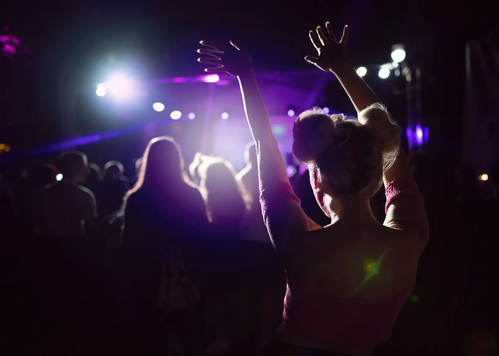 Silhouette of a dancer with arms raised at an open-air concert